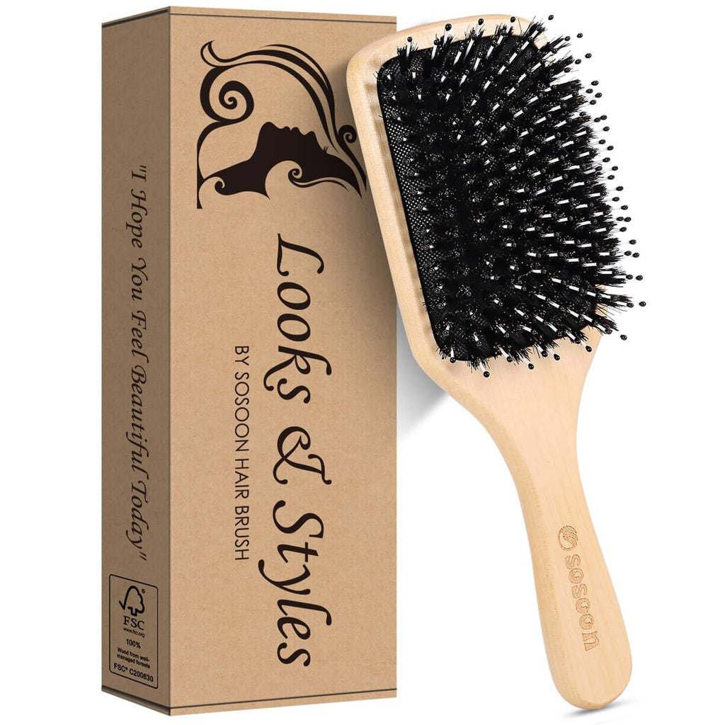Wooden paddle hairbrush with black boar bristles beside product box