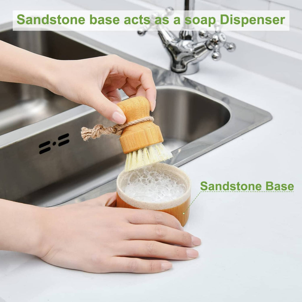 Wooden dish brush with soap dispenser cup beside sink, held by hands