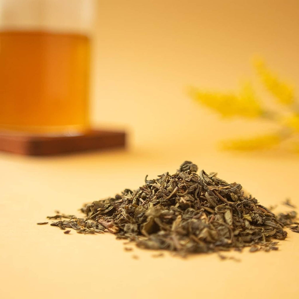 Organic green tea leaf pile on surface, dark green curled pellets