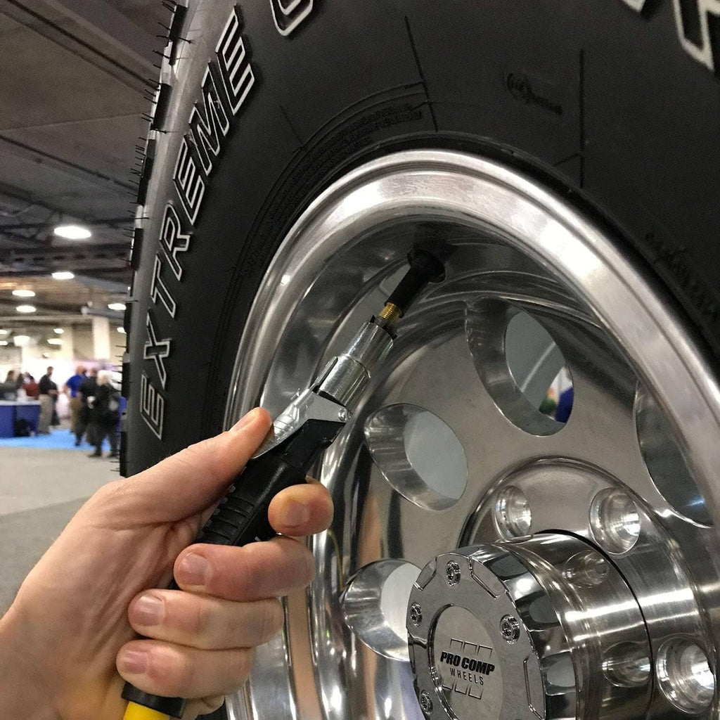 Tire inflator connector held at a car wheel valve on a chrome rim
