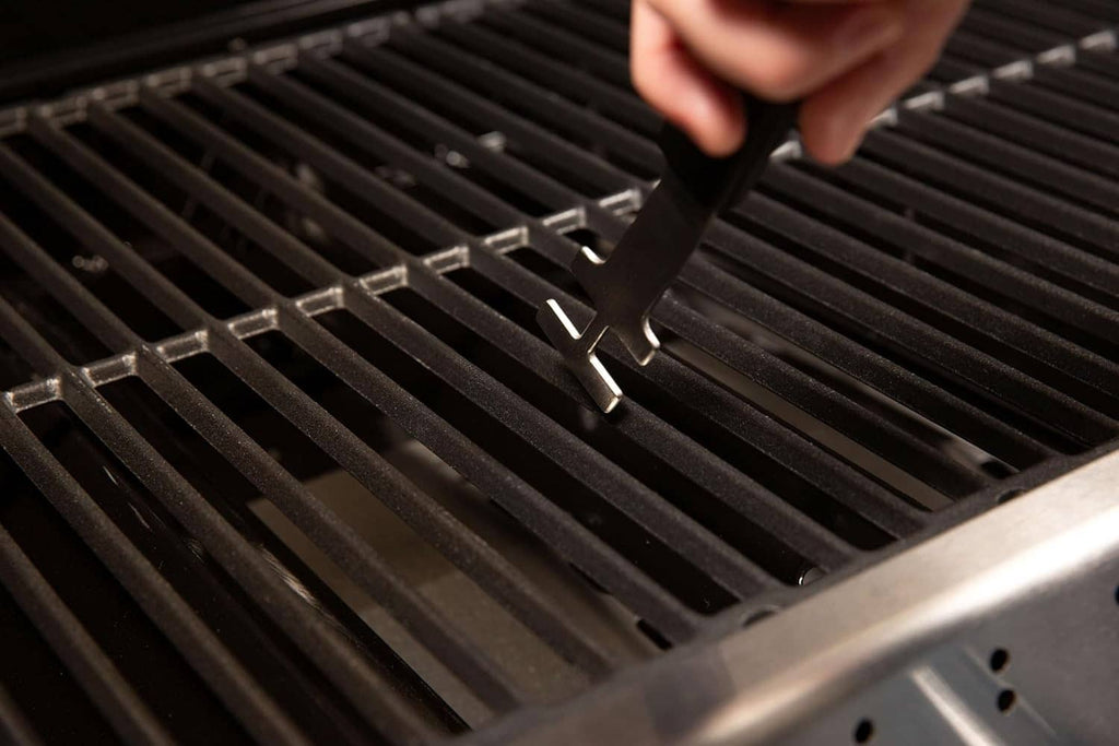 Grid lifter tool lifting a black grill grate using the fork