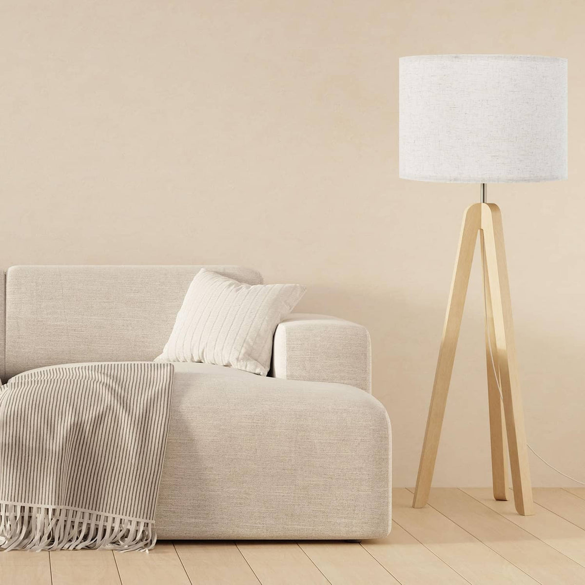 Beige linen drum floor lamp shade standing near a sofa with throw blanket