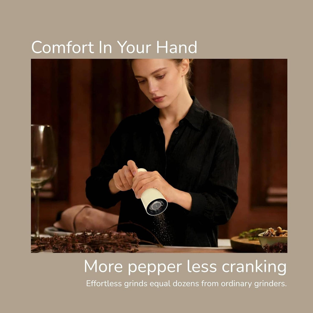 Salt and pepper grinder set held in hand by a person at a dining table