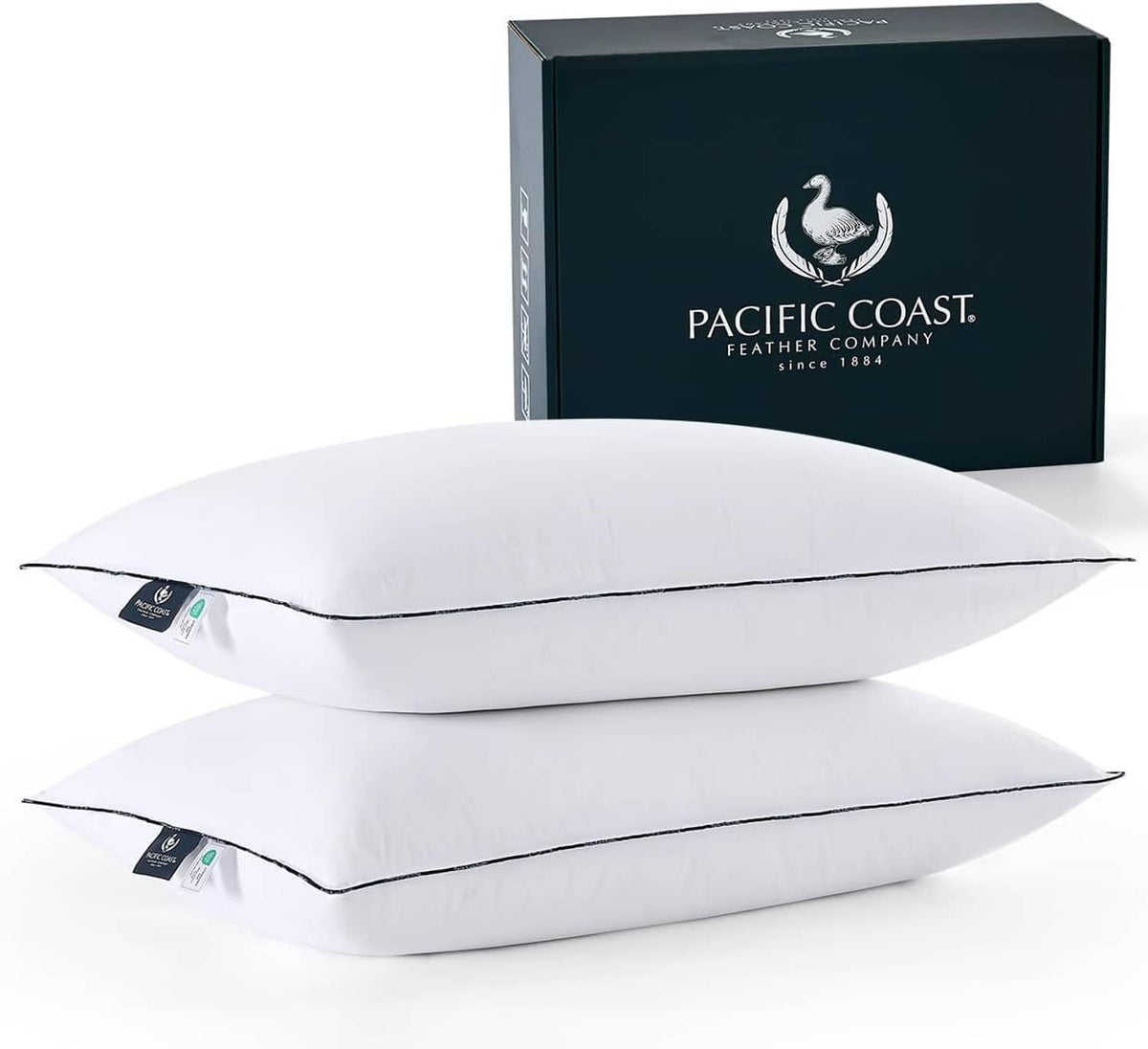 Set of white down bed pillows with dark piping, stacked with packaging box