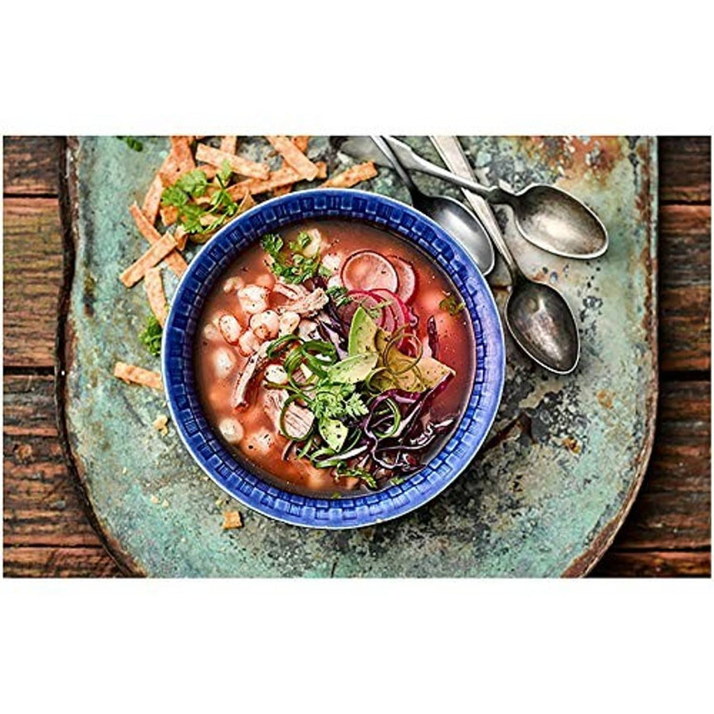 Serving bowl of beans with chopped onions and herbs, with spoons on side