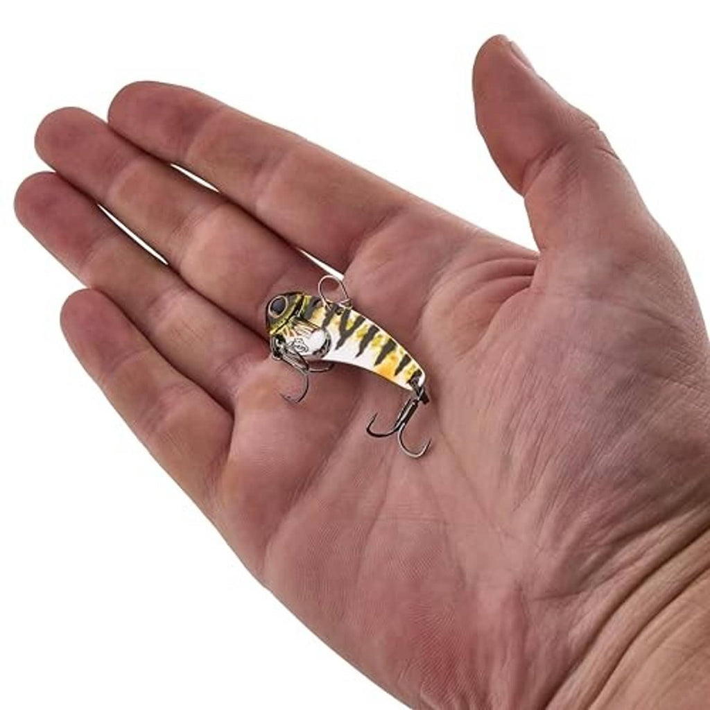 Blade bait fishing lure in hand, yellow-and-green pattern with two treble hooks