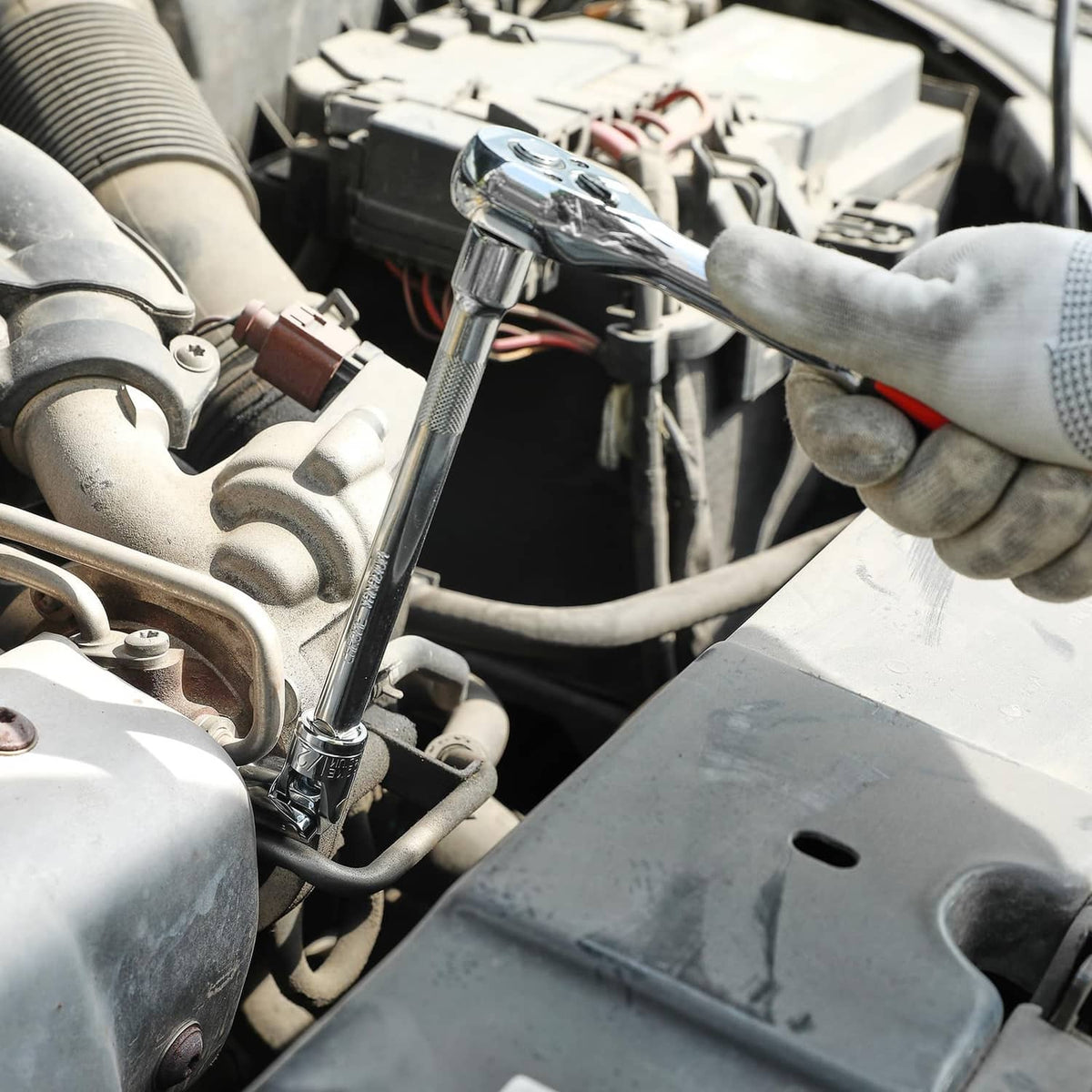 Universal joint socket on extension tool in an engine bay held by gloved hand
