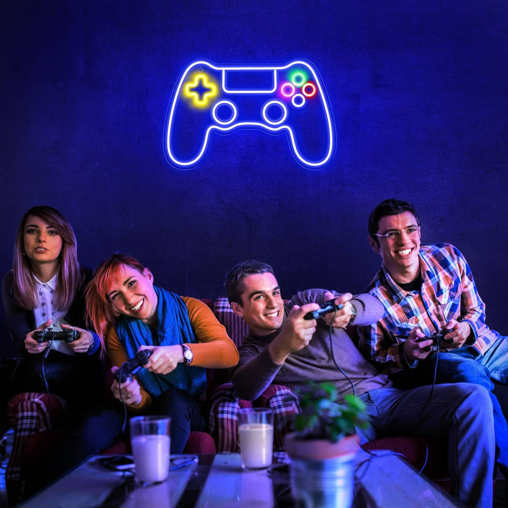 Gaming controller LED neon sign glowing above friends playing video games at a table.