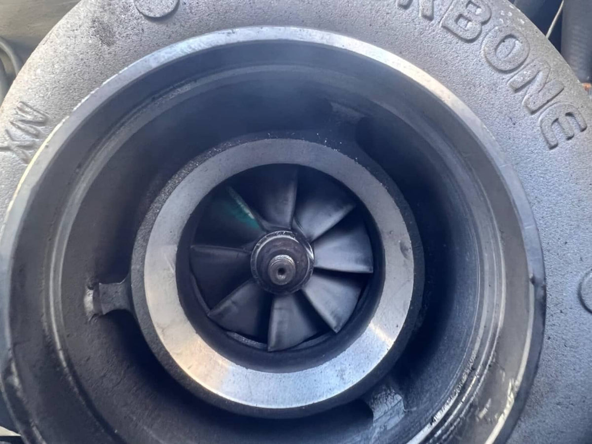 Turbocharger compressor wheel inside circular housing, metallic and dark fan blades