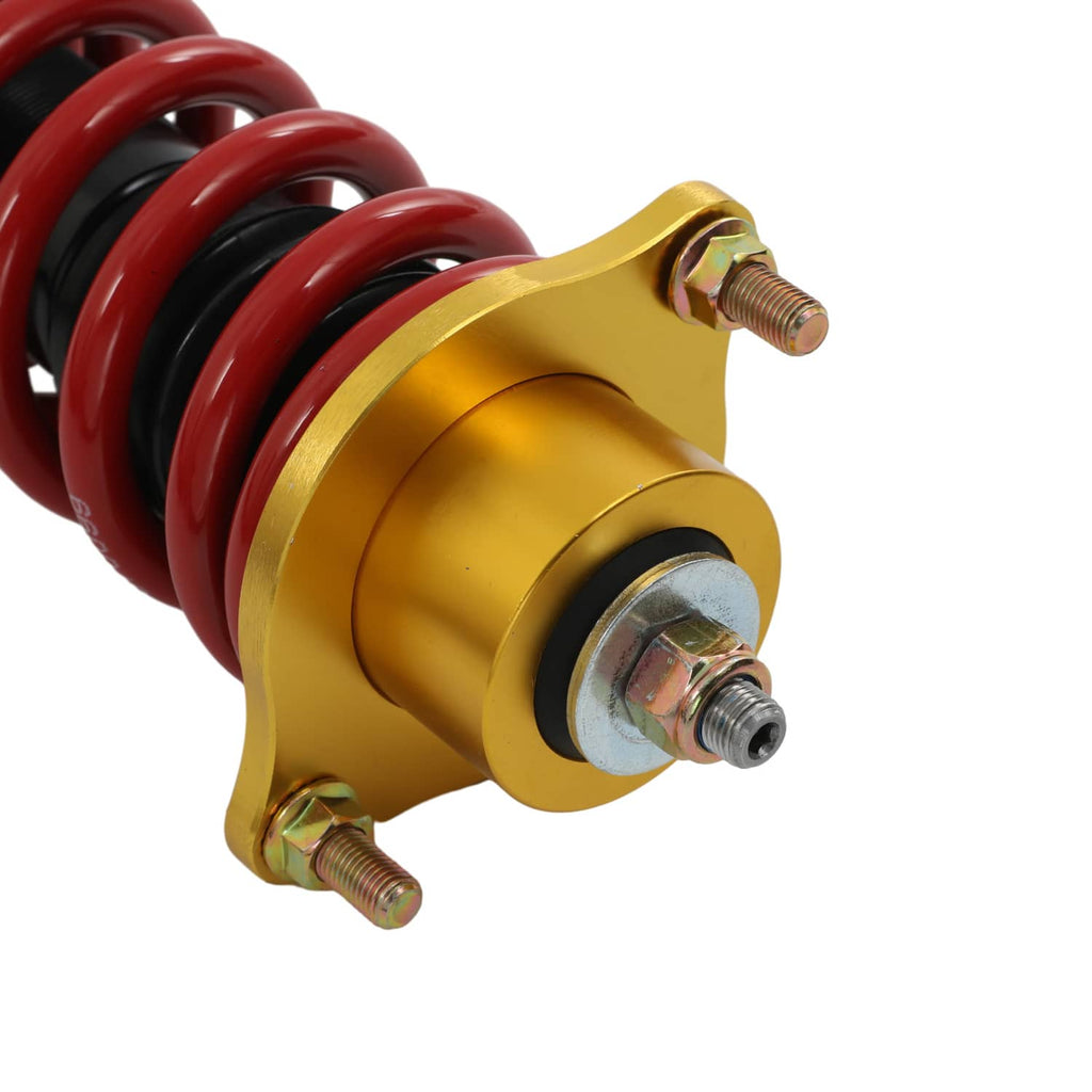 Close-up coilover with gold upper mount, threaded studs, and red spring coils.