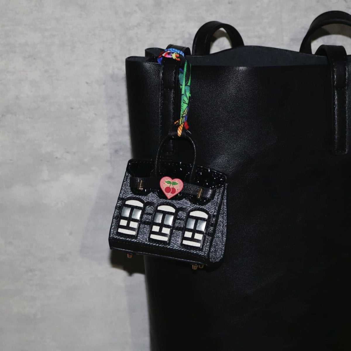 Black mini backpack keychain pouch with heart tag and white building window pattern.