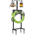 Black metal garden hose holder with green coiled hose and arched hook frame