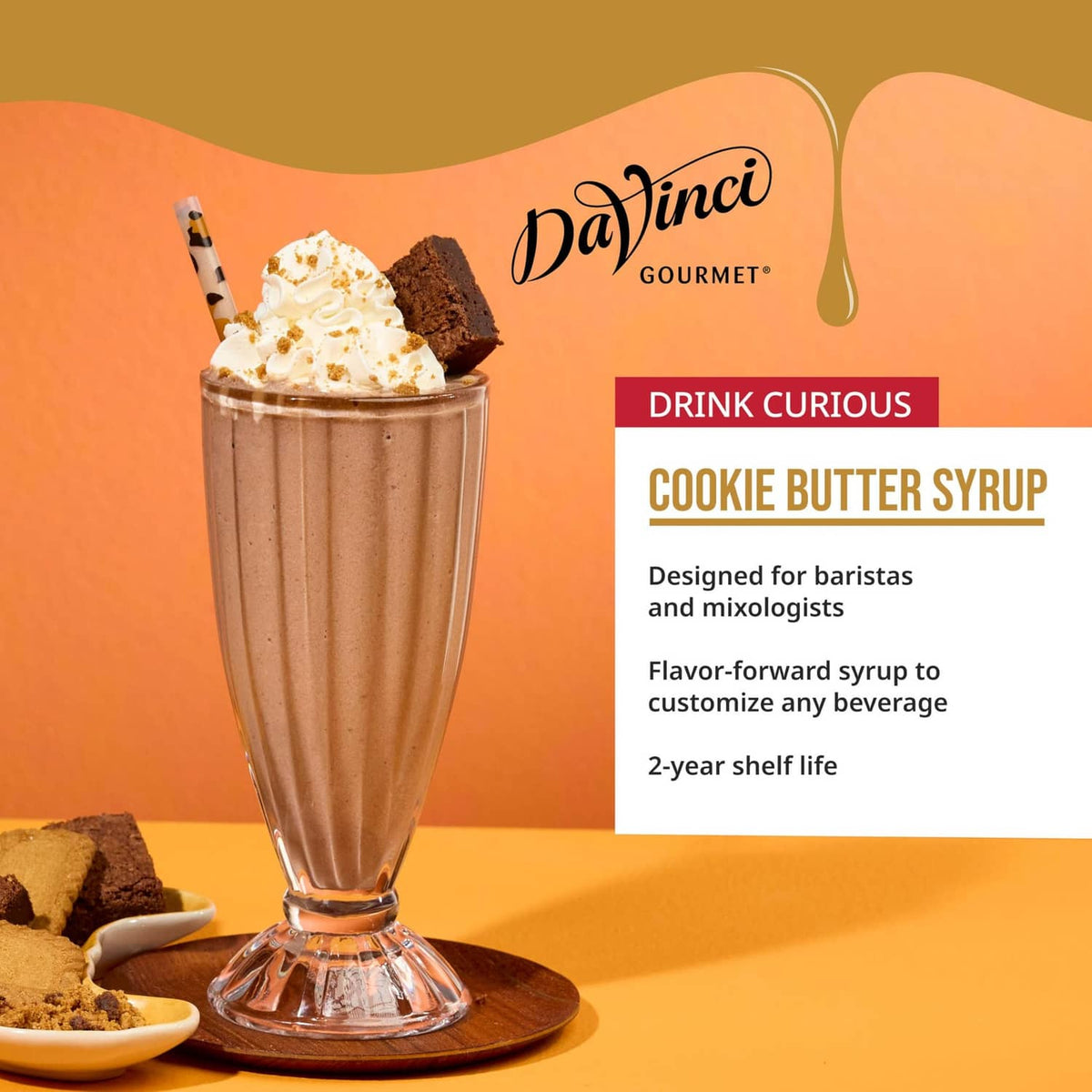 Cookie butter syrup milkshake in a tall glass with whipped topping and cookies