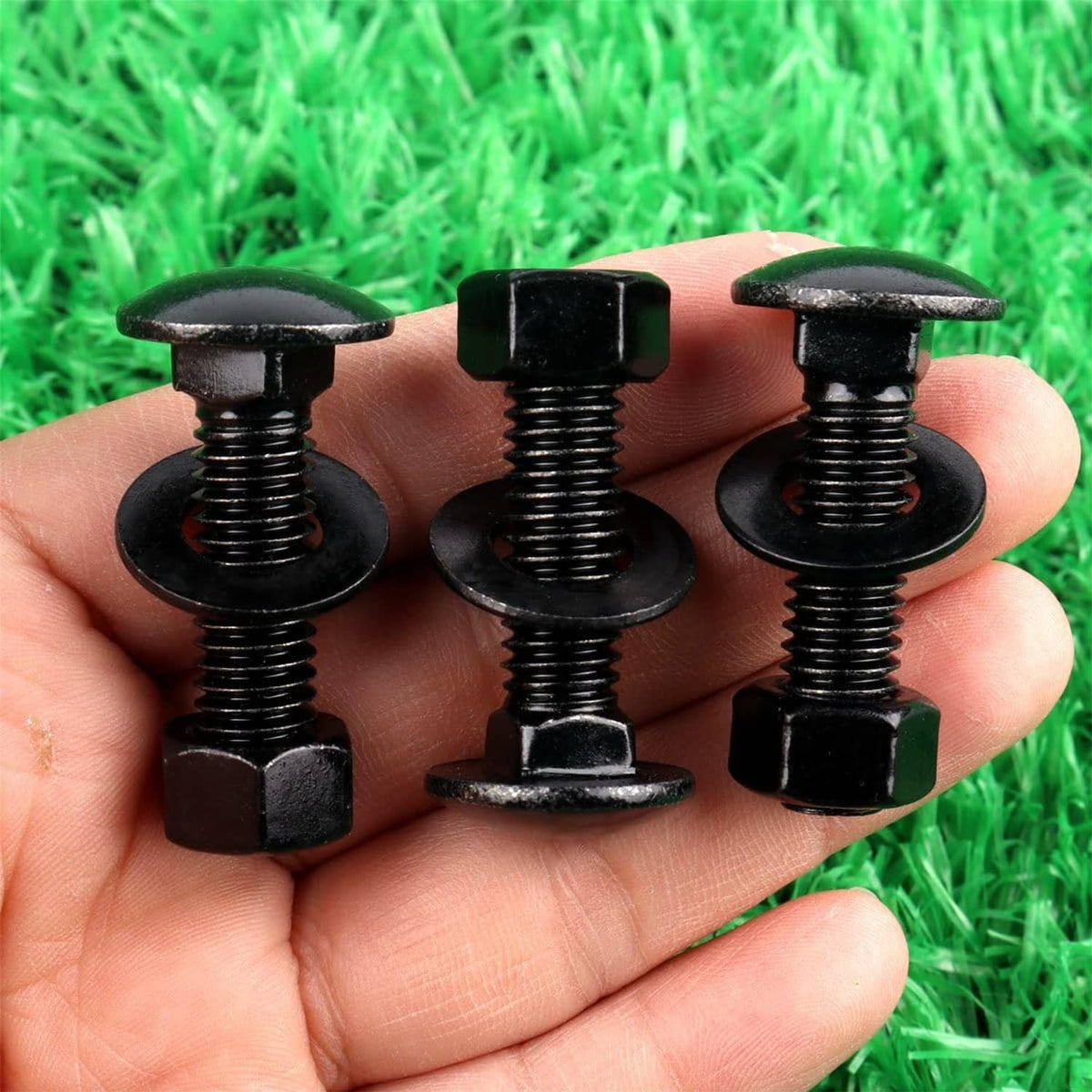 Black carriage bolts held in hand, showing threaded shanks and rounded heads