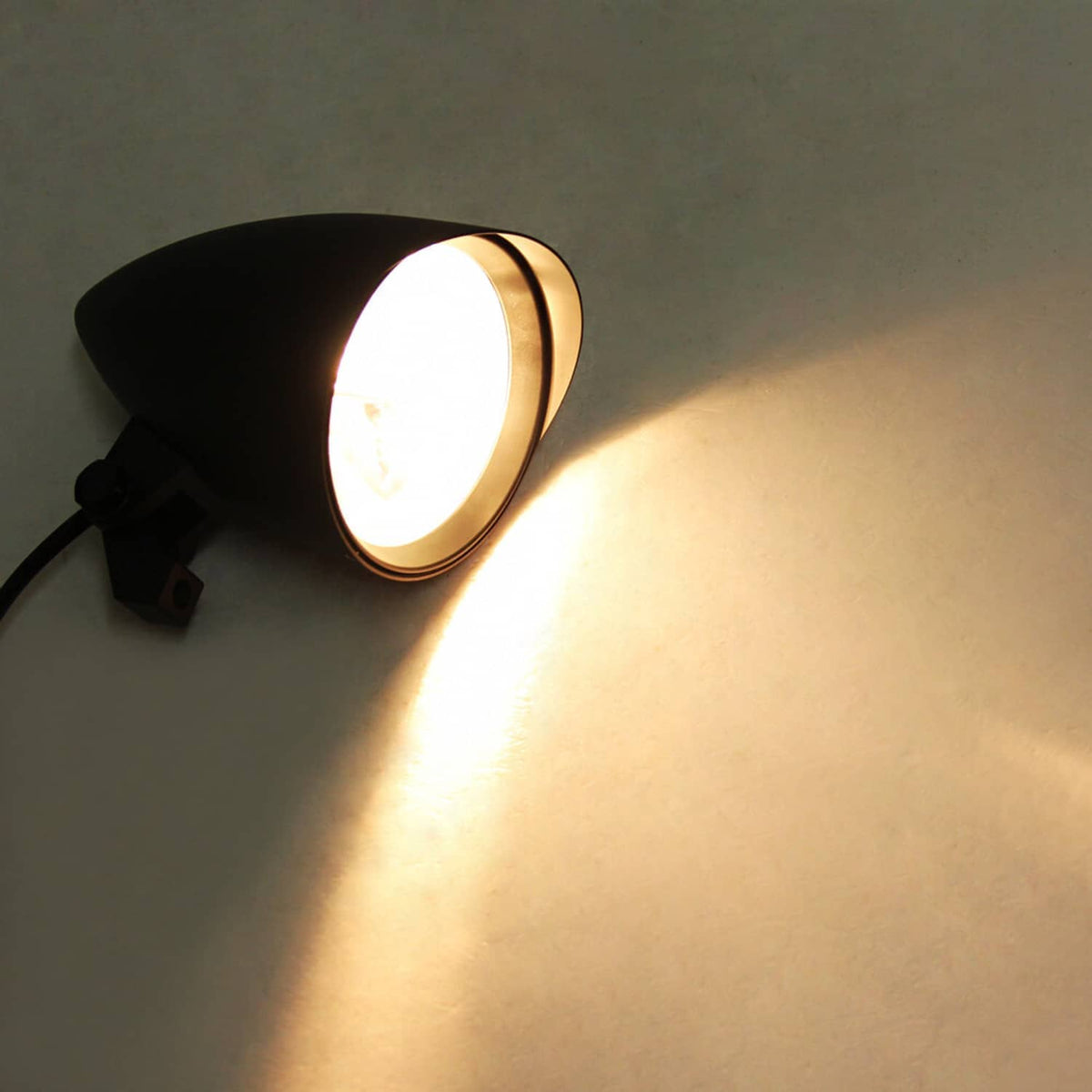 Motorcycle bullet headlight mounted on bracket with warm illuminated beam