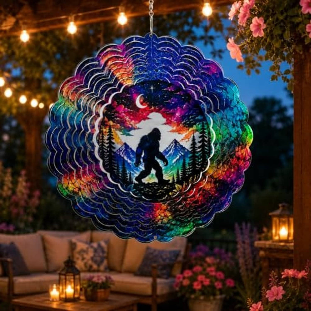 Bigfoot wind spinner hanging outdoors at night with multicolor galaxy design and pine trees