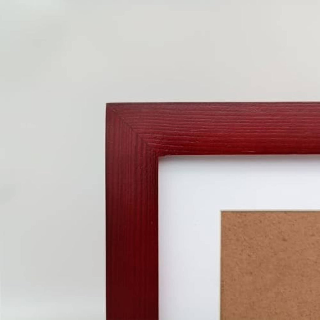 Close-up of red wood picture frame corner with white mat border