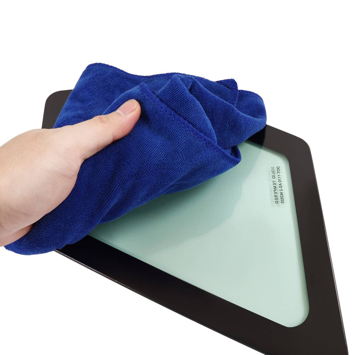 Hand wipes light green tinted cab window glass in black frame with blue cloth