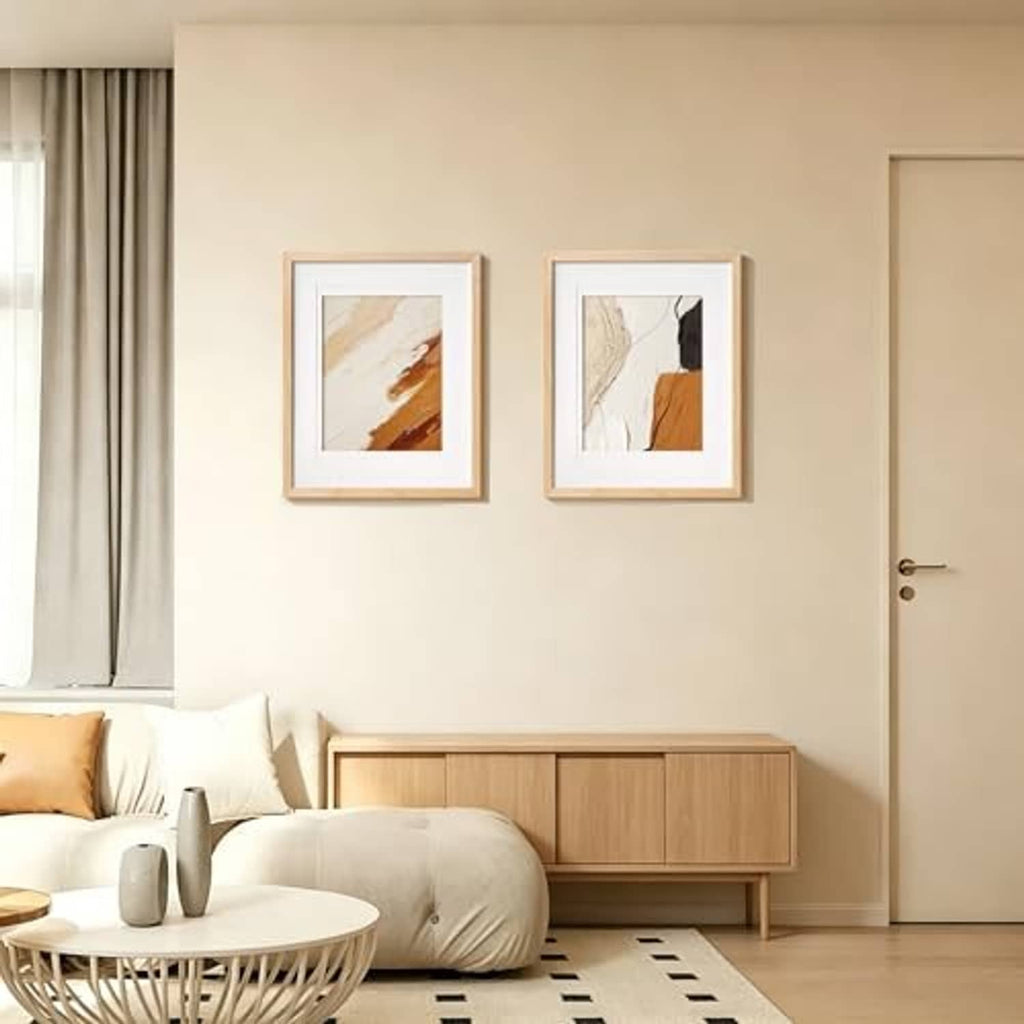 Two natural wood picture frames with white mats hung on a cream wall