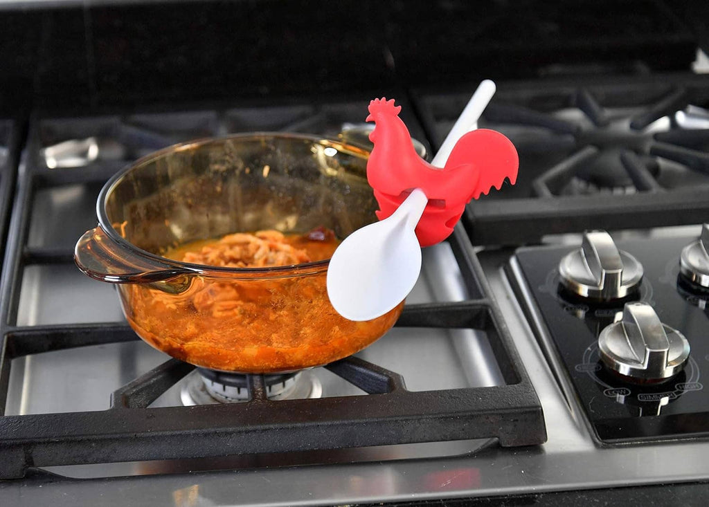 Red rooster spoon holder clip sitting on a stovetop pot handle