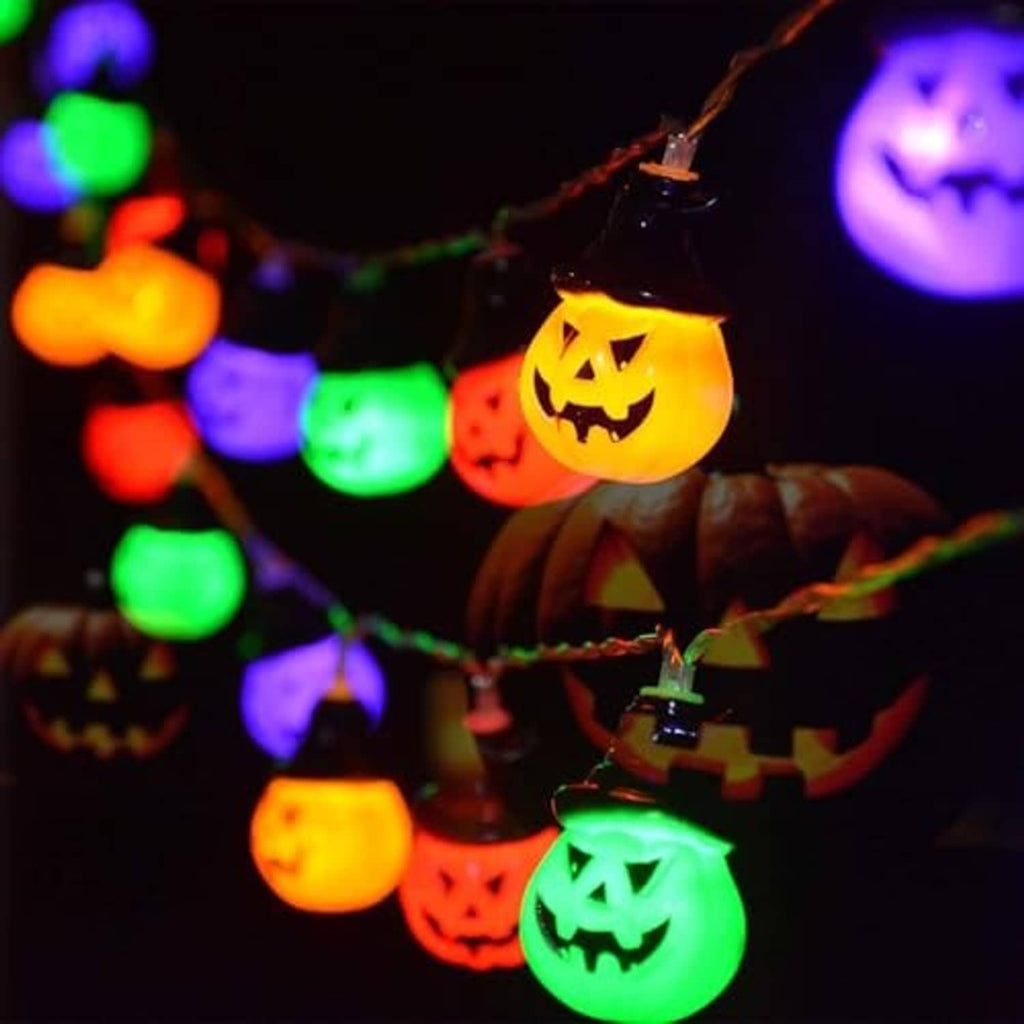 Close-up of glowing jack-o'-lantern pumpkin bulbs on a solar string light in multicolor.