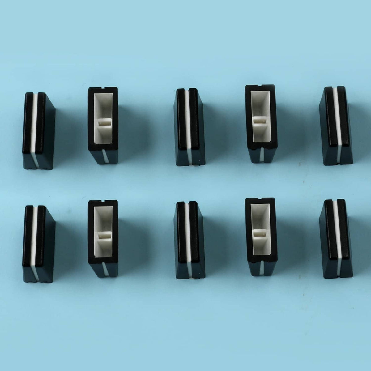 Black fader caps with light inner inserts, arranged in rows on a flat surface