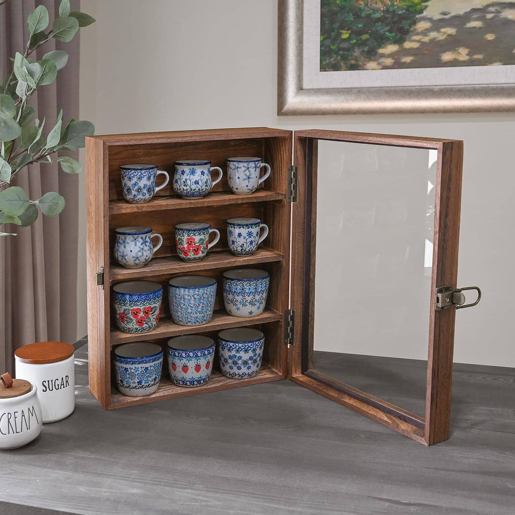 Wooden display cabinet with glass door open, showing blue ceramic mugs on shelves.