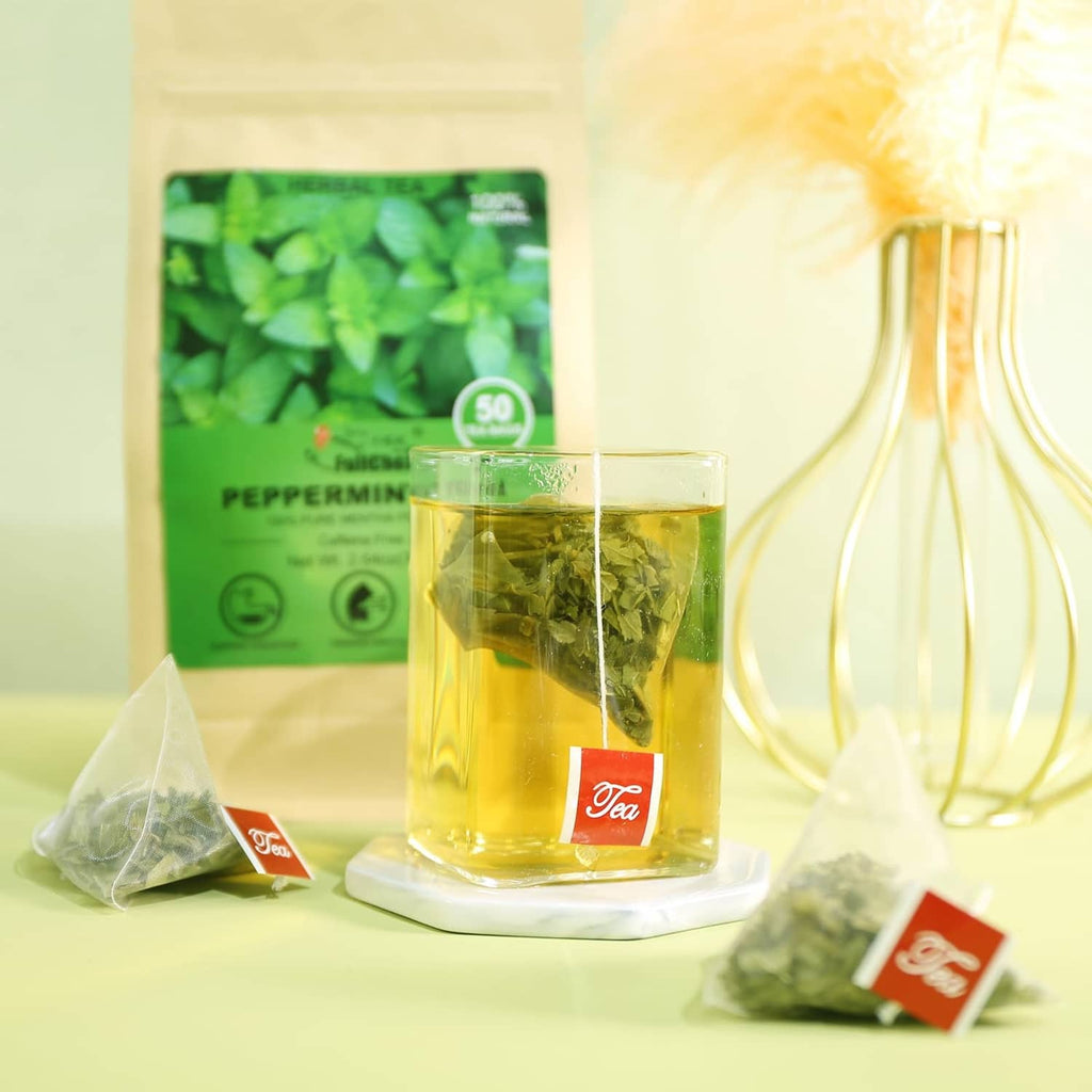 Peppermint tea bag pouch and cup of mint tea, with loose tea bag sachets