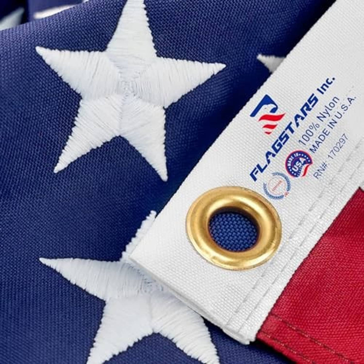 Close-up of American flag corner: brass grommet and stitched border on stars