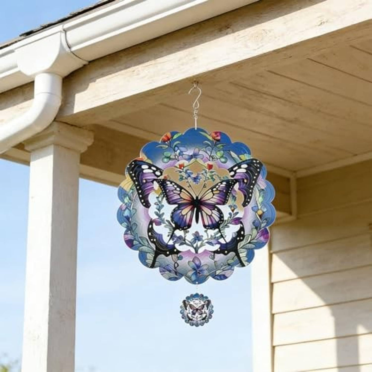 Butterfly wind spinner hanging from porch eave, circular reflective design with purple butterfly
