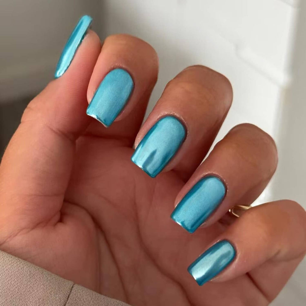 Close-up of teal blue chrome square press-on nails on fingers, glossy finish.