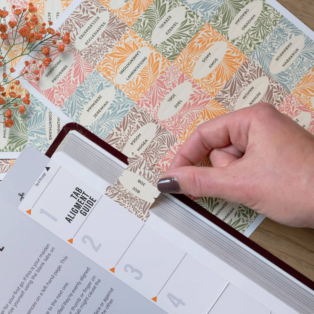 Bible book tabs being placed by hand along a book spine edge