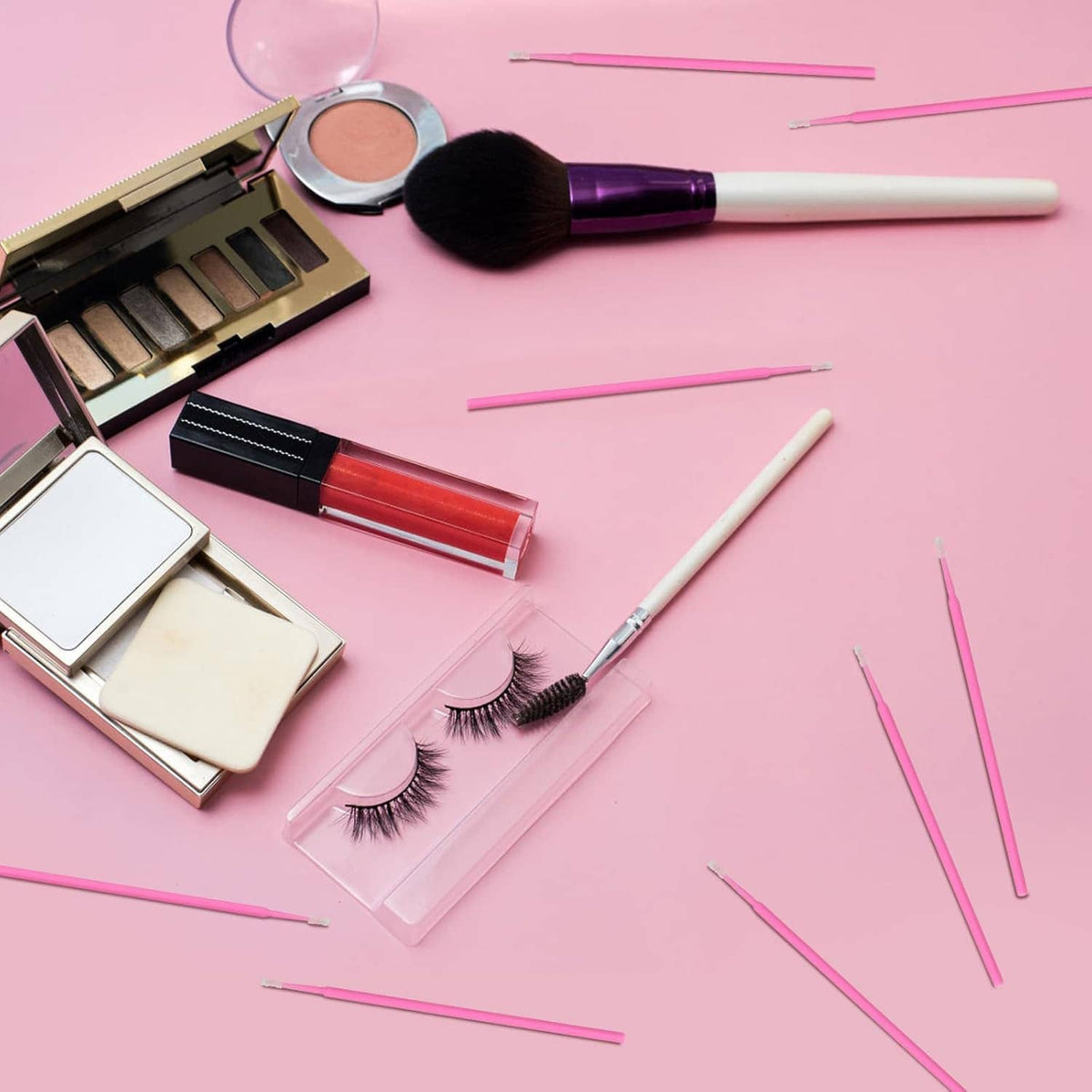 Pink micro swabs with foam tips alongside makeup tools on a flat surface