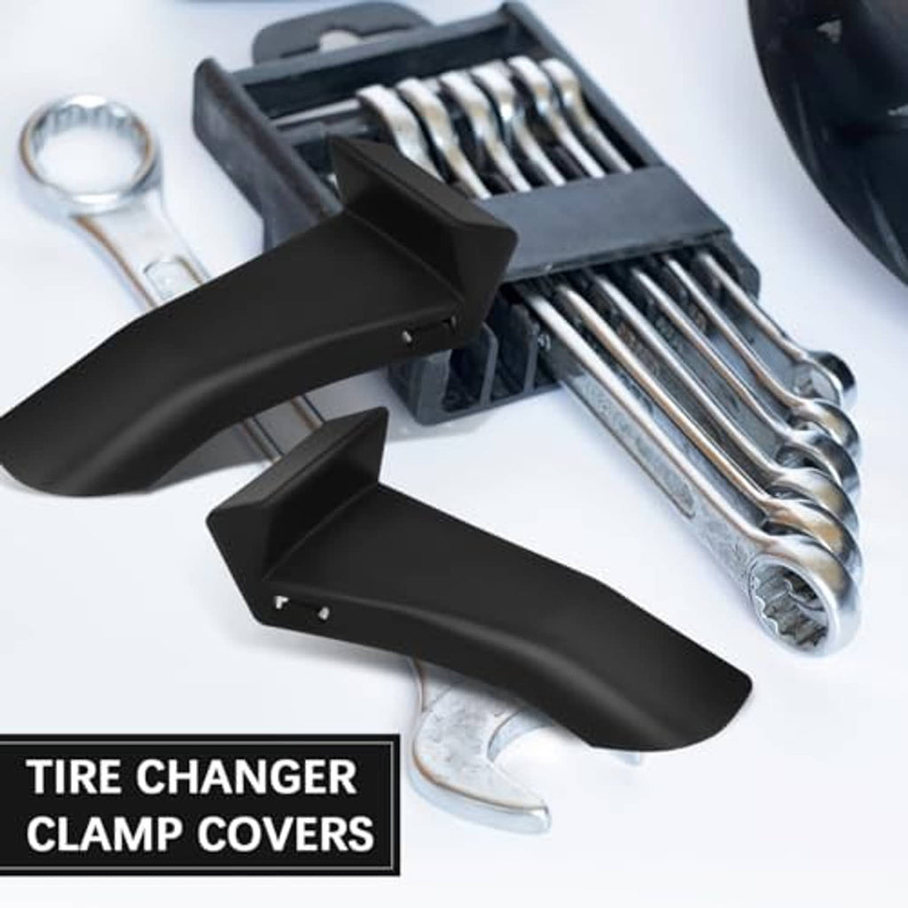 Black tire changer clamp covers with metal wrenches and tools beside them.