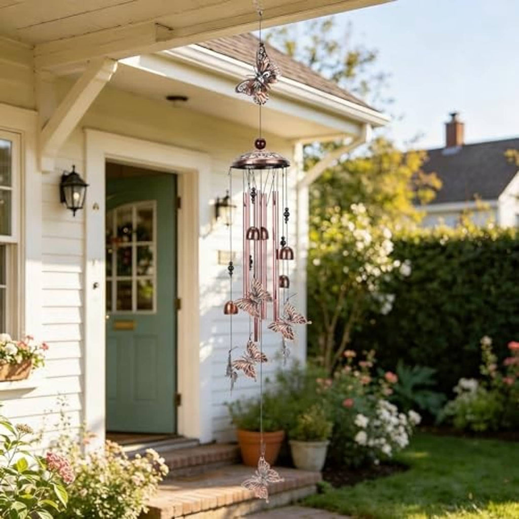 Copper-tone butterfly wind chime hanging from above with metal tube chimes
