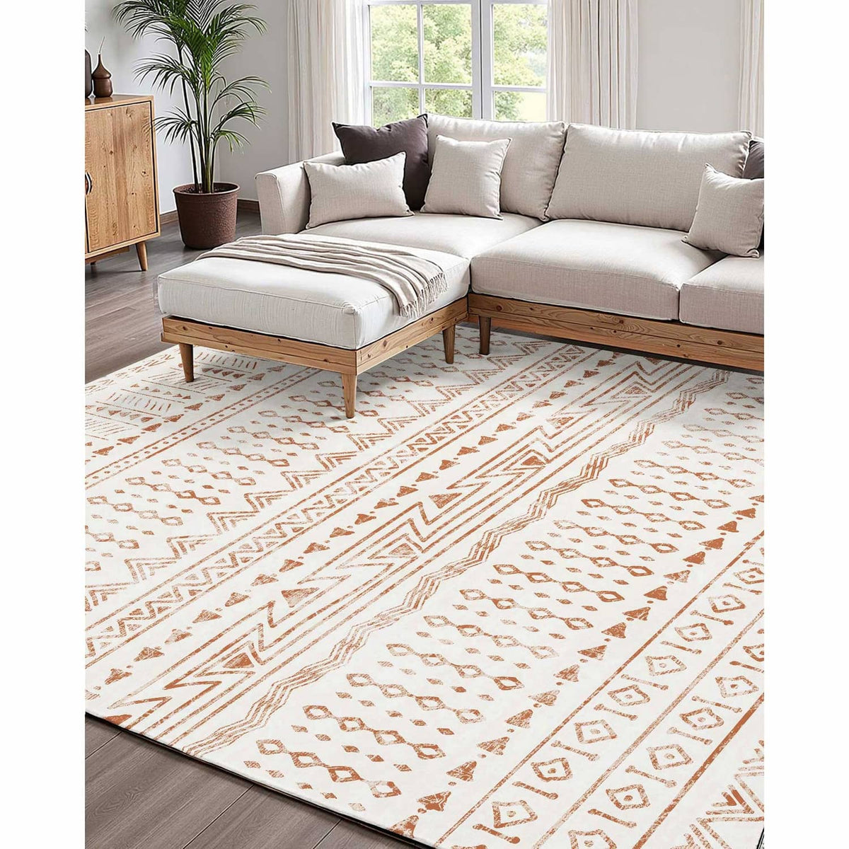 Beige geometric area rug with brown chevrons laid across a living room floor