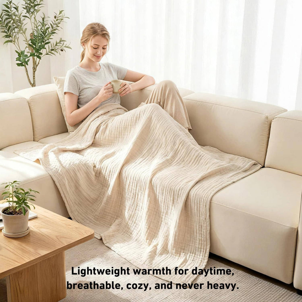 Cream cotton muslin blanket draped over a sofa, with lightweight layered fabric texture.