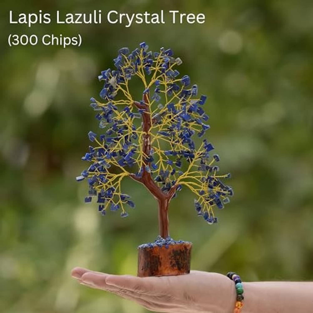 Lapis lazuli crystal tree with golden wire branches on amber wooden base, held in hand