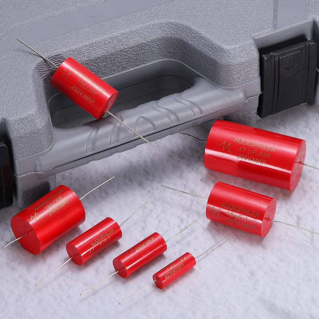 Set of red axial audio capacitors with metal lead wires, arranged on a surface