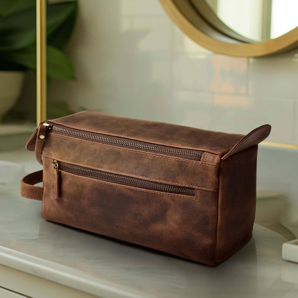 Brown leather toiletry bag with front zip pocket and adjustable carry strap