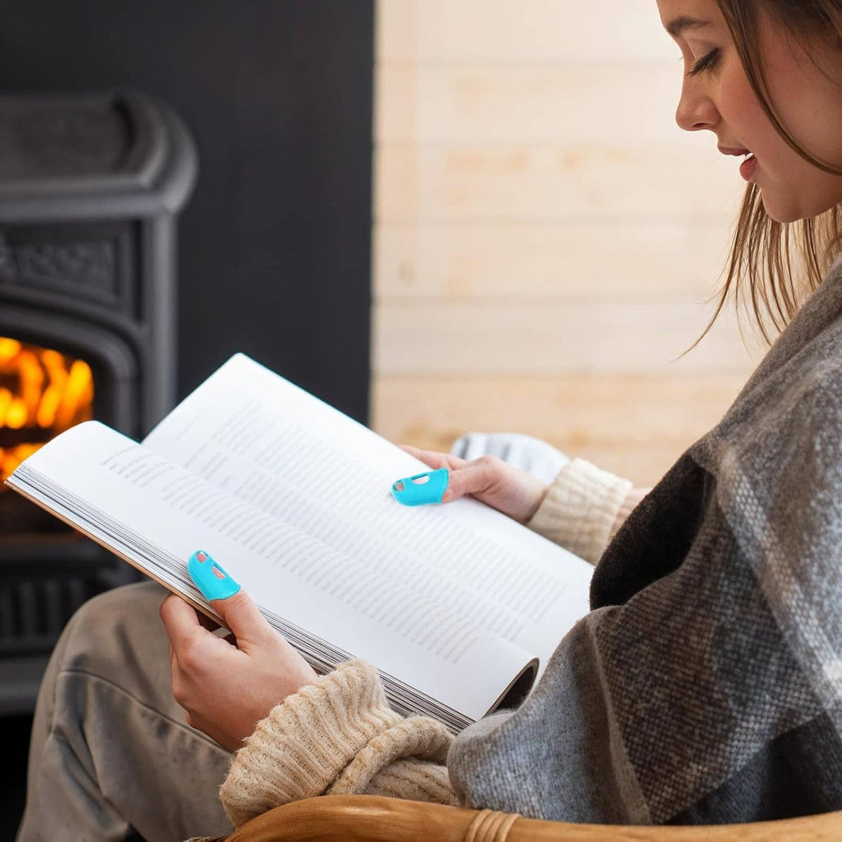 Person using blue silicone fingertip protectors on fingers while reading