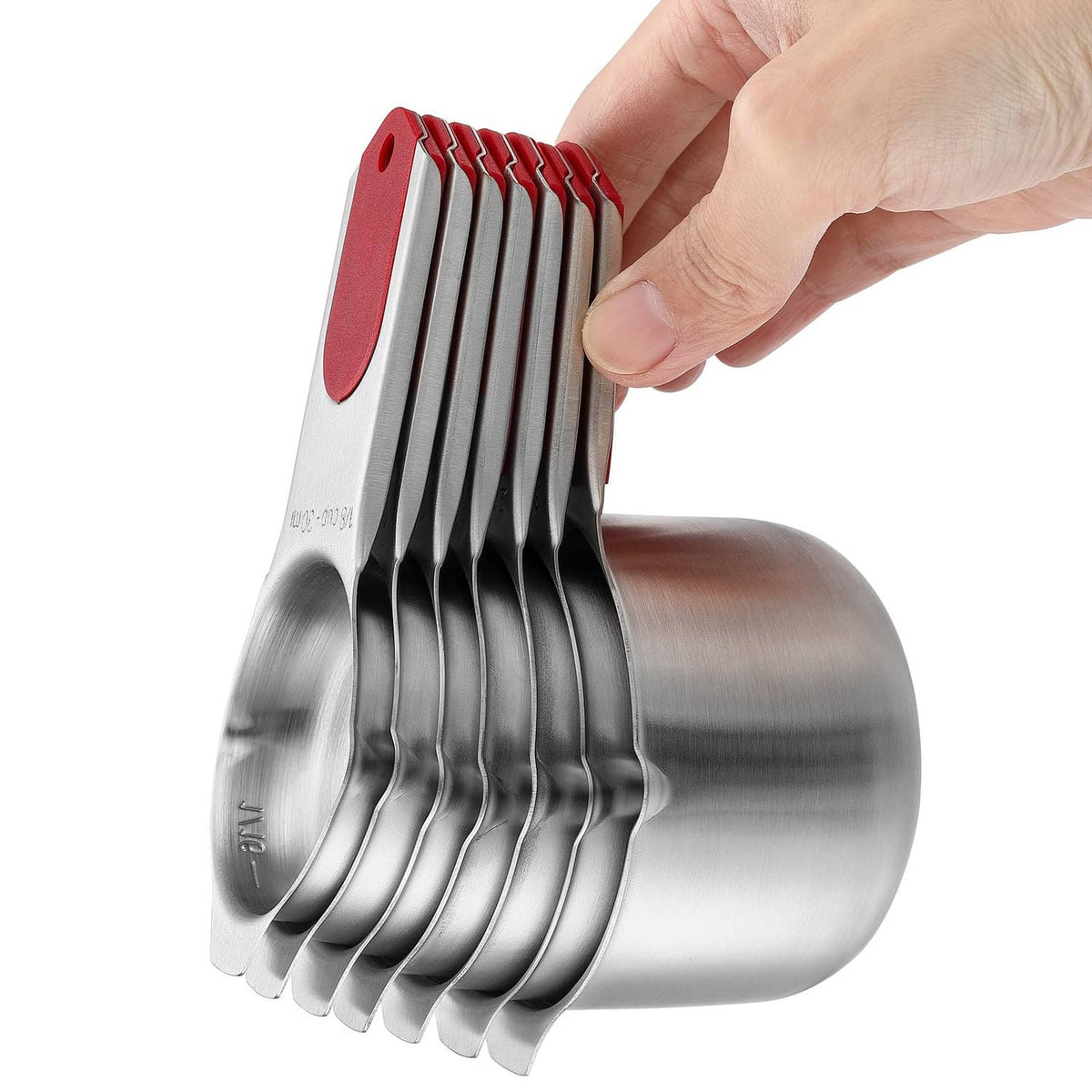 Hand holding nested magnetic measuring cups, stainless cups with red tabs
