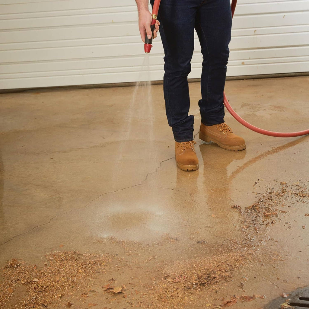 Person using red 3/4 in hose indoors, connected near the floor with spigot end.