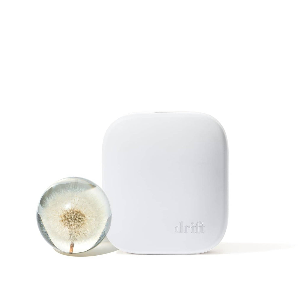 White plug-in home scent diffuser beside a small scent vial