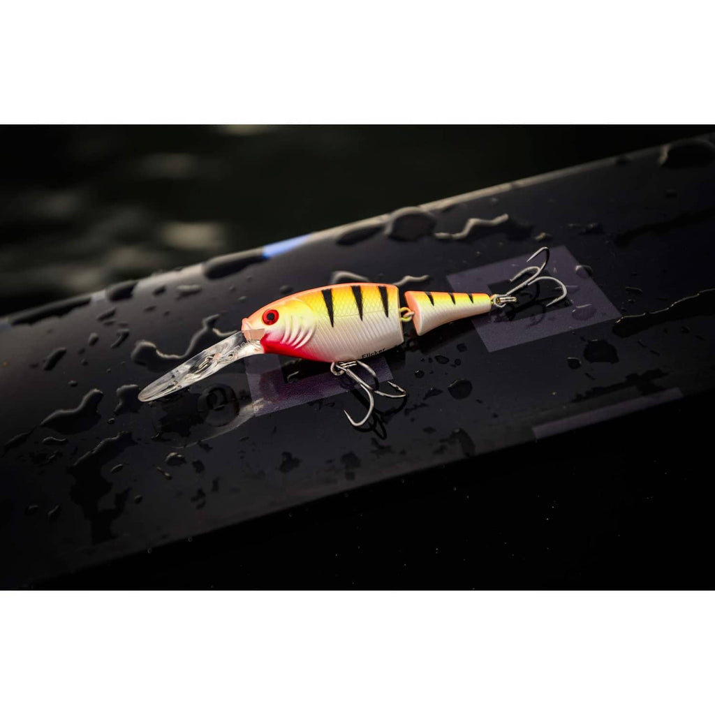 White and yellow crankbait lure with red stripes and treble hooks on dark tackle board