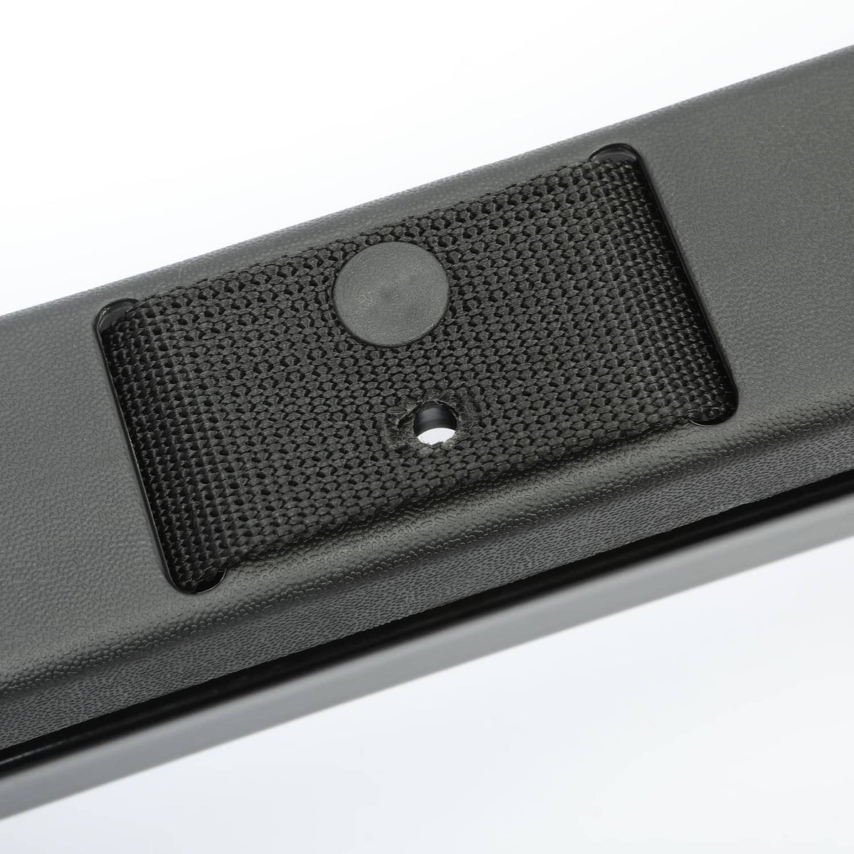 Close-up of black textured mounting pad with round screw hole on bracket bar