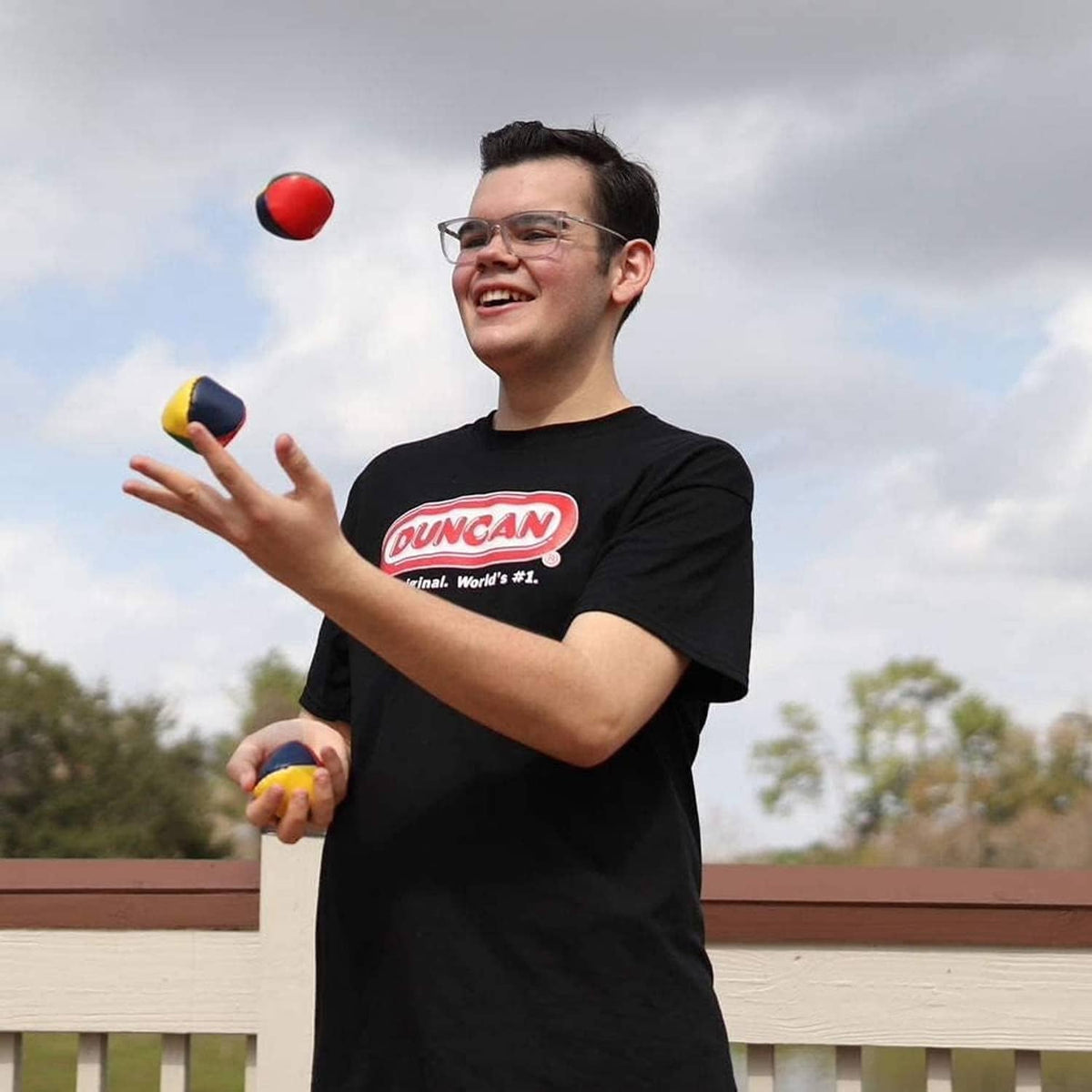 Multicolor vinyl juggling balls in hands, with red, blue, yellow, and green balls.