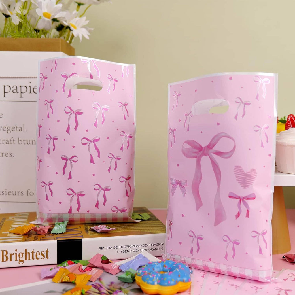Pink bow-pattern plastic treat bags standing upright with top handle cutouts