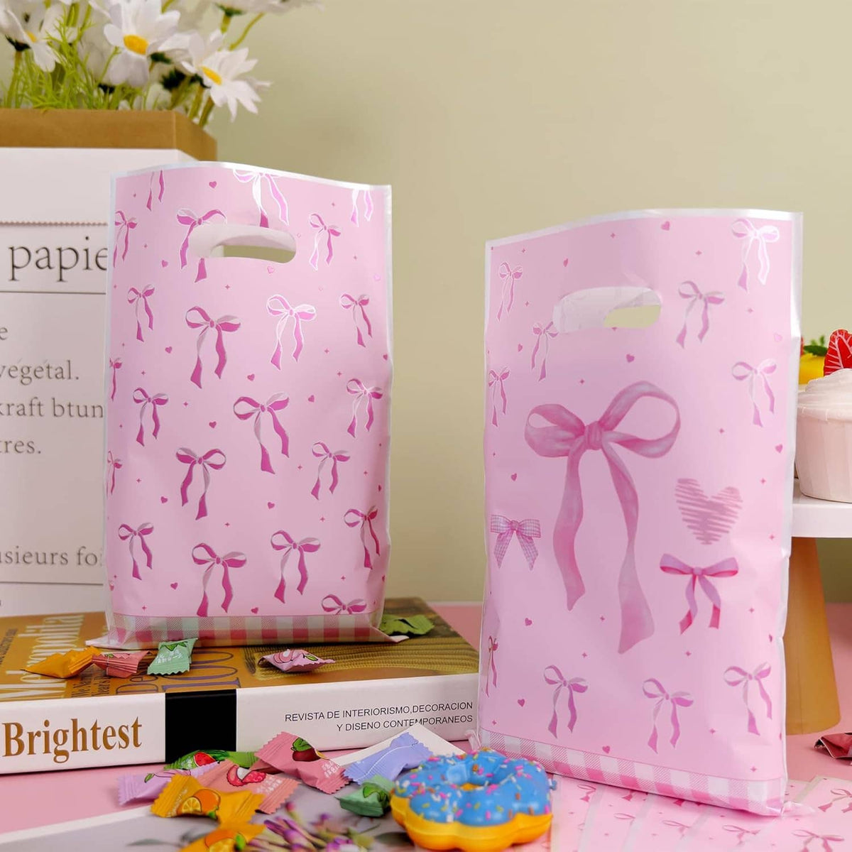 Pink bow-pattern plastic treat bags standing upright with top handle cutouts