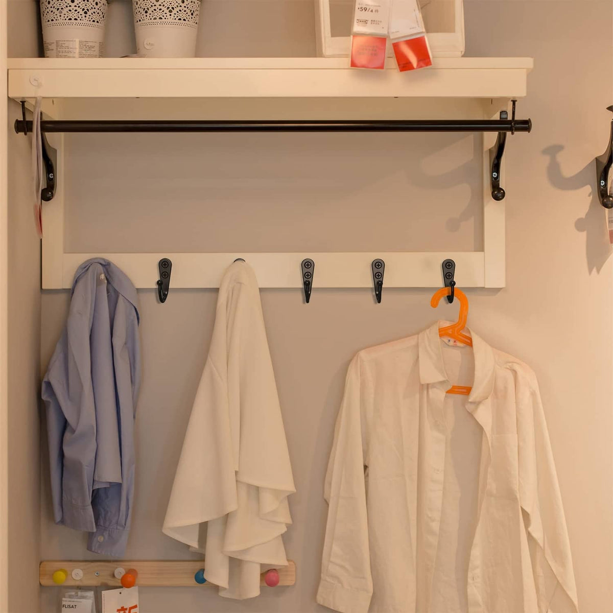 Black wall coat hook set holding jackets and a hanging bag